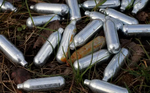 Discarded nitrous oxide canisters lying on grass