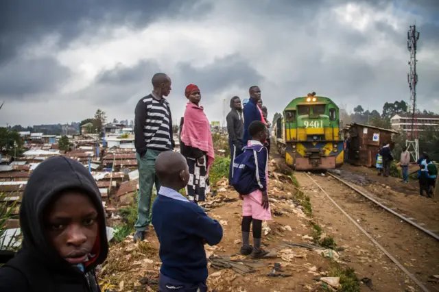 Residents wait to board the morning passengers train at a normal train stop in Kibera