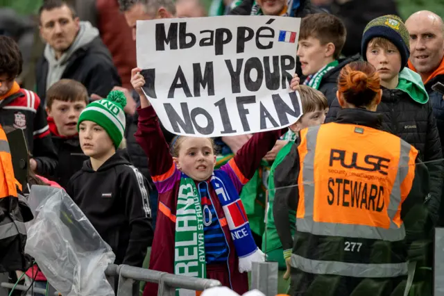 A young fan holds up a Mbappe poster