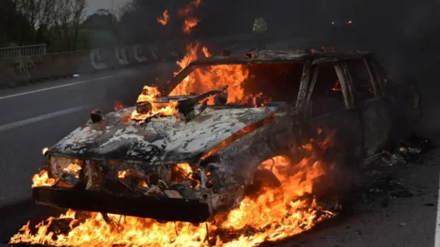 A car, which, according to an eyewitness, was brought from a scrapyard by protesters, burns as people demonstrate against the French government's pension reform, on a road in Rennes, France, March 28, 2023, in this image obtained from social media. Ewen Bazin/via REUTERS