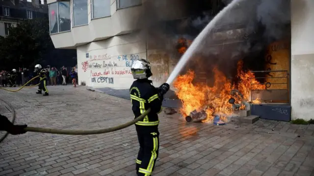 French firefighters try to extinguish a burning BNP Paribas bank office during clashes at a demonstration as part of the tenth day of nationwide strikes and protests against French government's pension reform in Nantes, France