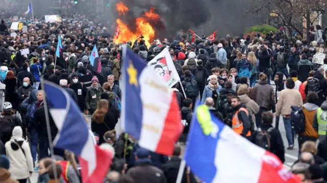 Protesters hold French flags near a fire during clashes at a demonstration as part of the tenth day of nationwide strikes and protests against French government's pension reform in Paris, France, March 28, 2023.