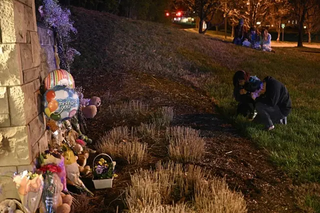 People gather at a makeshift memorial for victims outside the Covenant School building