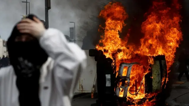 Protester in France in front of a burning car