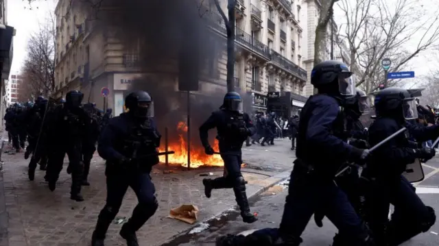 French riot police run past a fire during clashes at a demonstration as part of the tenth day of nationwide strikes and protests against French government's pension reform, in Paris, France, March 28, 2023. REUTERS/Gonzalo Fuentes