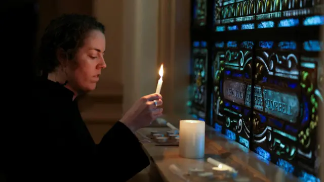 Rev. Keller Hawkins lights a candle during a community vigil held at Belmont United Methodist Church