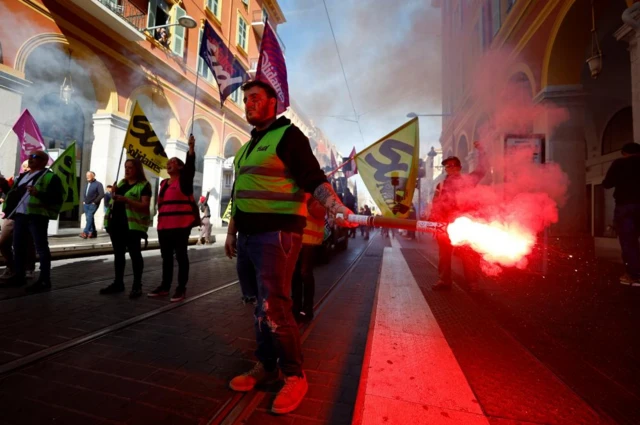 A man holds a red flare during a demonstration in Nice, France