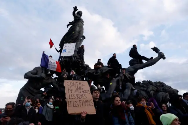 Protesters hold a French national flag as they stand on the statue of the Place de la Nation during a demonstration against the French government's pension reform law, in Paris, France, on 28 March 2023