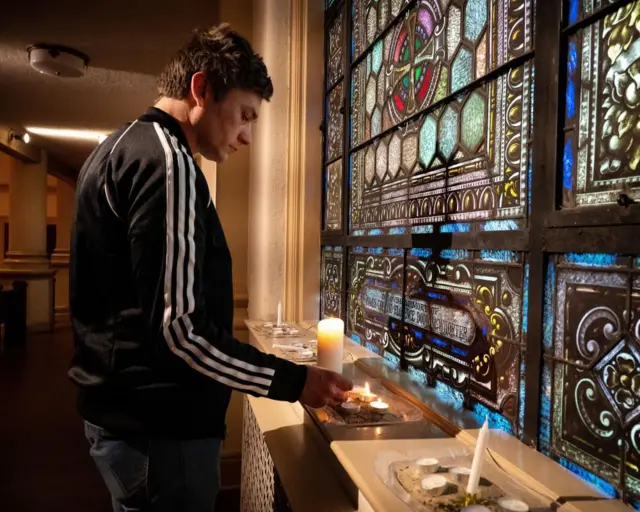 A man lights a candle at a vigil