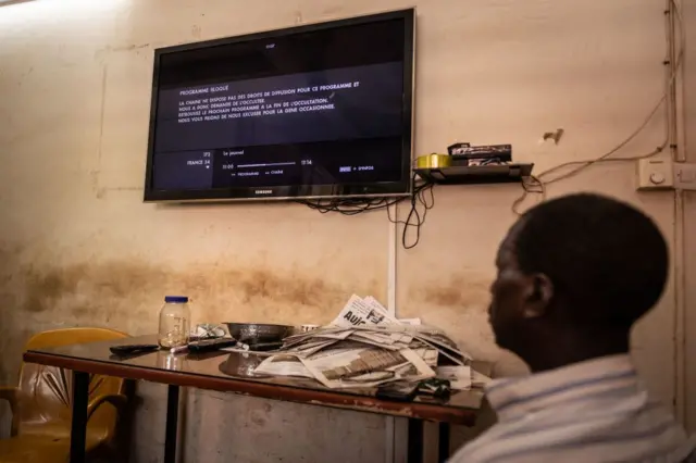 A man watches a television showing the cut signal of the France 24 channel, hours after the ruling junta in Burkina Faso decided to suspend the channel, in Ouagadougou, on 27 March.