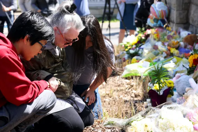 Shepherd Hollis, Katie Jo Hollis, and Sophie Hollis pray at the memorial for the fallen at the school entrance after a deadly shooting at the Covenant School in Nashville, Tennessee, US March 28, 2023