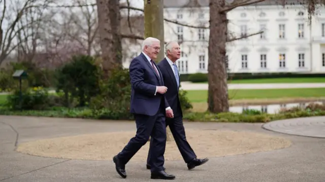 Charles and the German President walk through the palace gardens