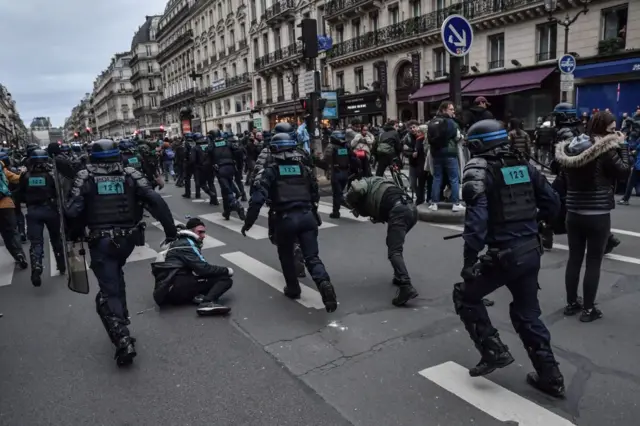 Police in riot gear charge a line of protesters