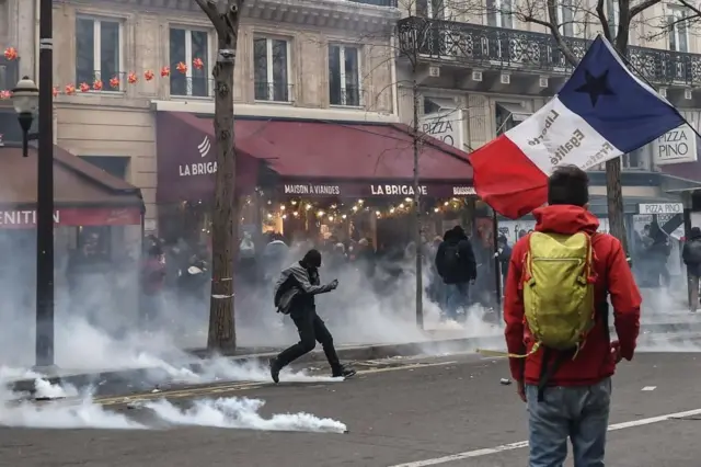 Protester kicks tear gas cannister away from himself while others look on