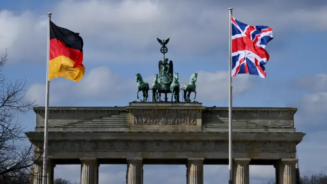 The German and UK flags in front of the Brandenburg Gate in Berlin