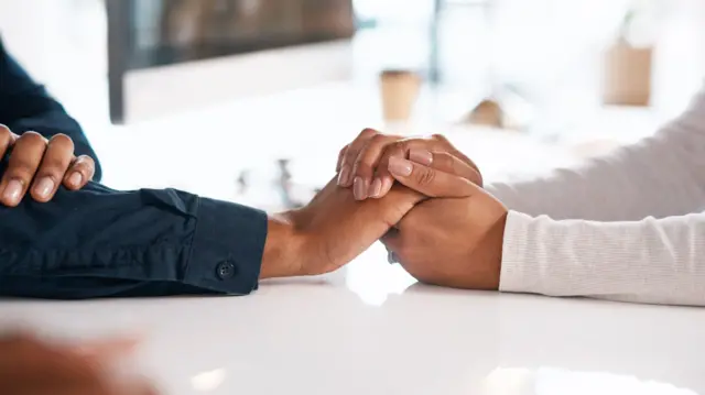 People comforting each other by holding hands - generic shot