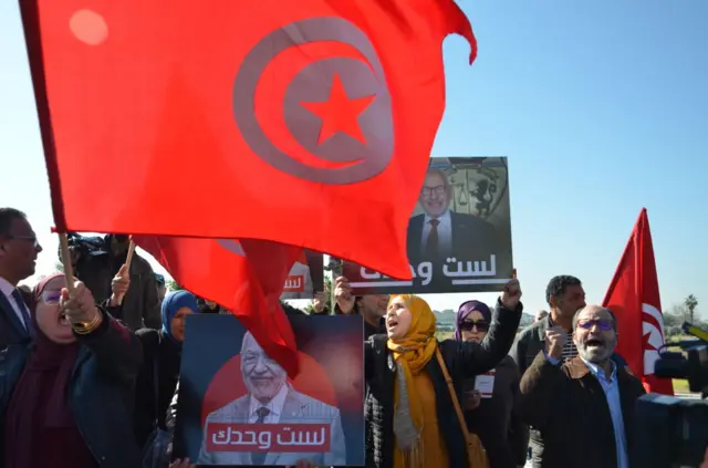 People holding signs and Tunisian flags to show support for Ennahdha Movement leader Rached Ghannouchi