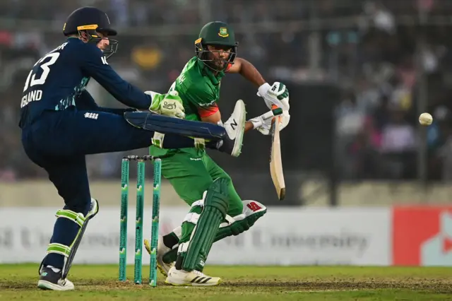 Bangladesh's Mahmudullah (R) plays a shot as England's captain Jos Buttler gestures during the second one-day international (ODI) cricket match between Bangladesh and England