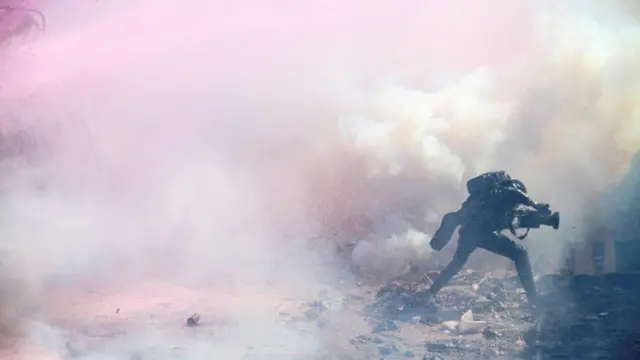 A journalist runs through teargas lobbed by riot police officers to disperse the convoy of Kenya's opposition leader Raila Odinga