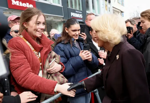 Camilla, the Queen Consort greets a member of the public as she visits a farmer's market