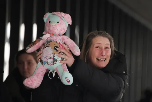 Cheryl Korbel, mother of nine-year-old Olivia Pratt-Korbel, grinning while holding a pink and blue teddy aloft