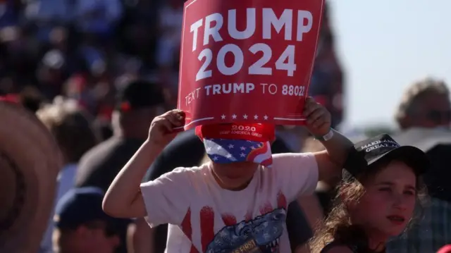 A child holds a campaign sign ahead of the first rally for the re-election campaign of former U.S. President Donald Trump at Waco Regional Airport in Waco, Texas,