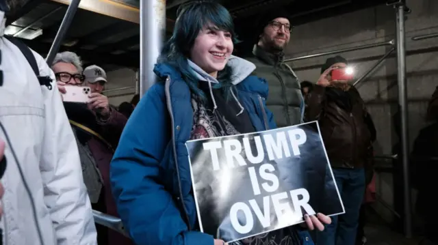 Woman holding sign that says 'Trump is over'