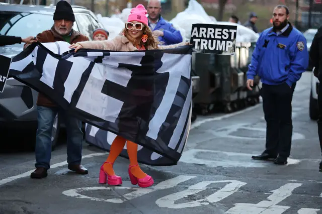 Protester holding a sign which reads "arrest Trump"