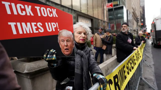 An anti-Trump protester holds a placard outside Trump Tower