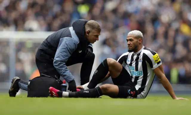 Newcastle midfielder Joelinton receives treatment on the field at the Etihad