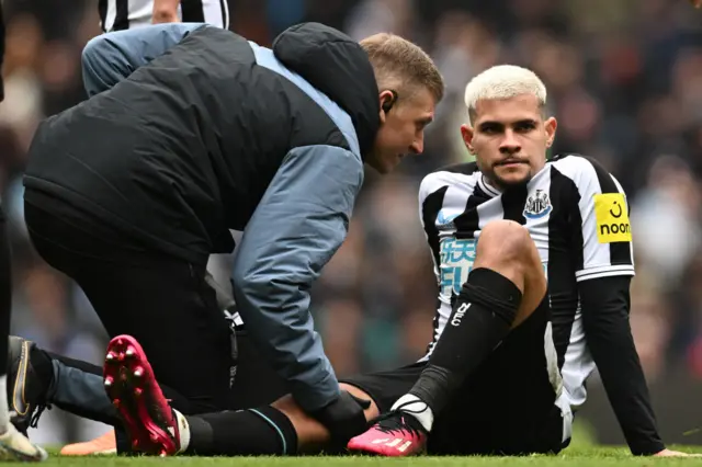 Newcastle midfielder Bruno Guimaraes receives treatment on the pitch at the Etihad