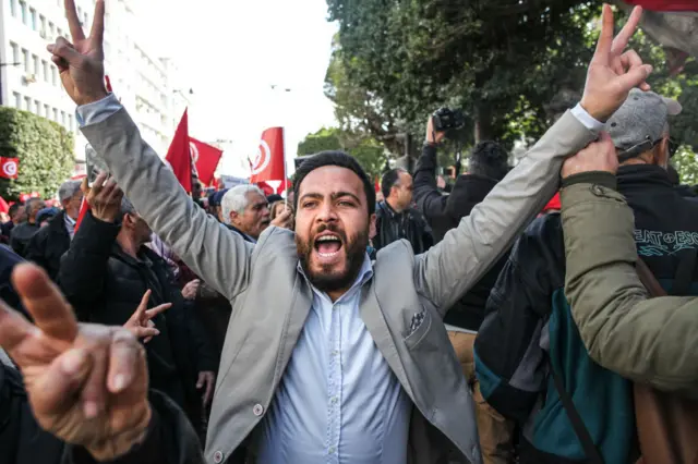 Demonstrators chant slogans and flash the V-for-victory sign on Sunday.