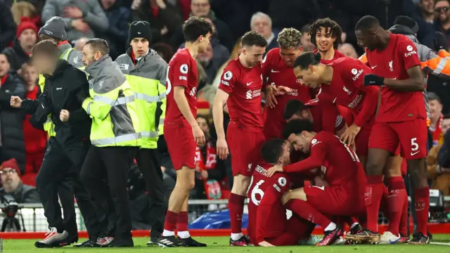 The pitch invader is led away by stewards at Anfield