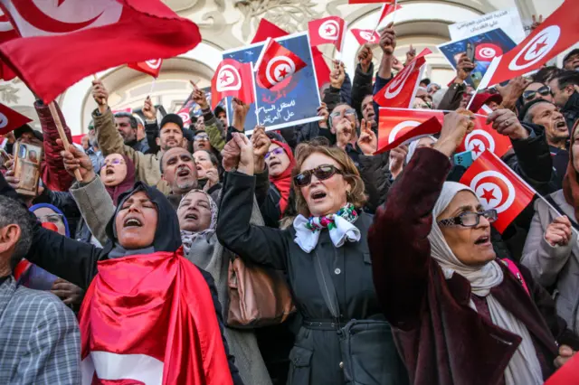 Demonstrators shout slogans while making the victory sign and raising flags of Tunisia, during a demonstration held by the National Salvation Front opposition alliance, in Tunis, Tunisia, on March 5, 2023