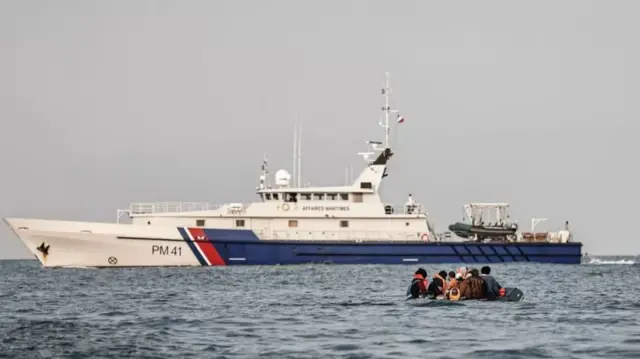 A French patrol vessel approaches a migrant's dinghy in the English Channel