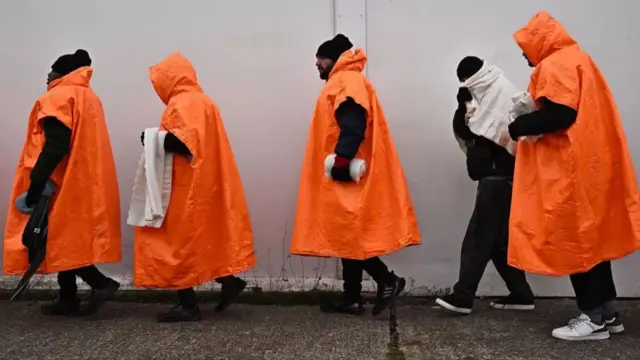 Migrants standing in a queue waiting to be processed in Kent