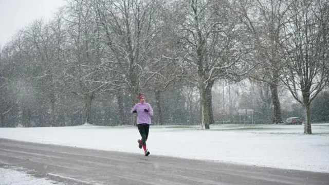 A jogger takes an early morning run in the snow at the Long Walk near Windsor Castle