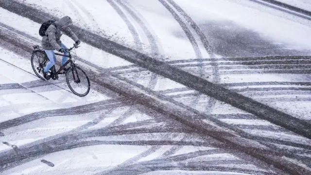 A man rides a bicycle during a snowfall in Limburg, Netherlands