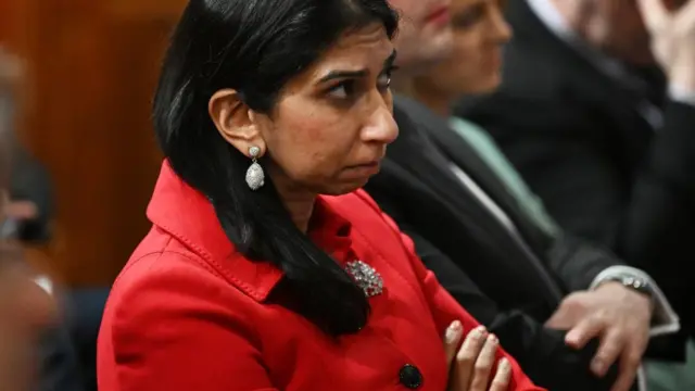 Suella Braverman listens during a press conference