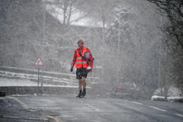 A postman walking in the snow in Oldham, Greater Manchester