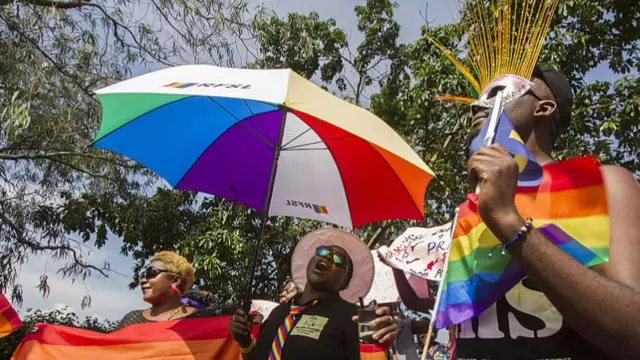 People holding rainbow flags and umbrellas take part in the Gay Pride parade in Entebbe, Uganda - August 2015