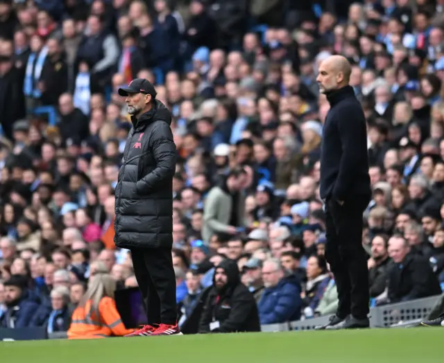 Pep Guardiola and Jurgen Klopp watch on from the sidelines.