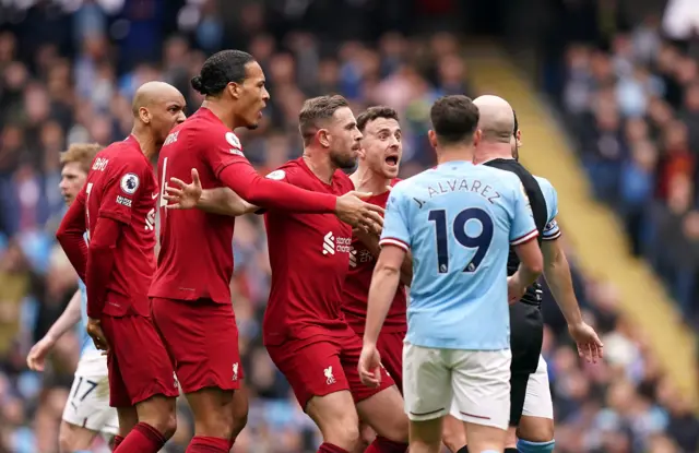 Liverpool players surround referee Simon Hooper.