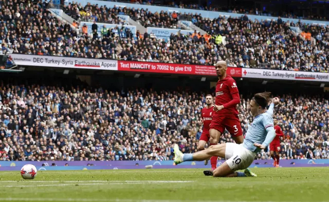 Jack Grealish slides in to score Man City's fourth goal v Liverpool.