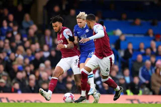 Mykhaylo Mudryk of Chelsea is challenged by Tyrone Mings and Ezri Konsa of Aston Villa