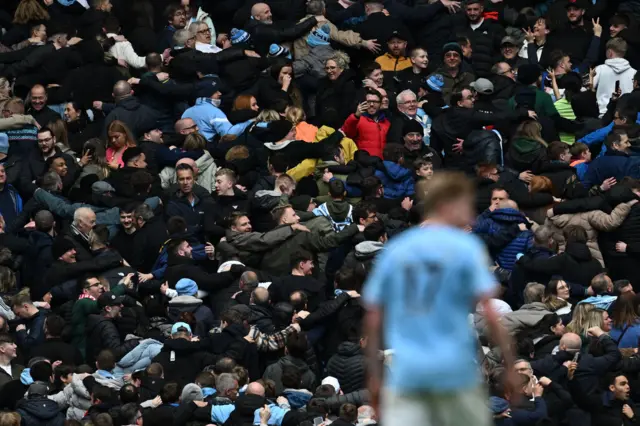 Man City fans celebrate their fourth goal with their signature 'Poznan' celebration.