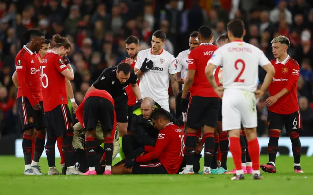 Manchester United's Casemiro receives medical attention after sustaining an injury as referee Felix Zwayer and the players look on