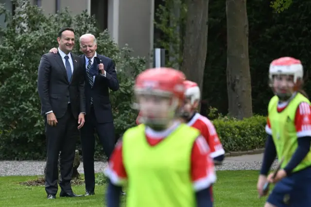 Joe Biden and Leo Varadkar talking, as they watch a game of camogie