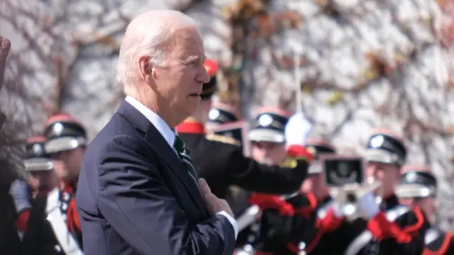 Joe Biden, hand on heart, listens to the US national anthem