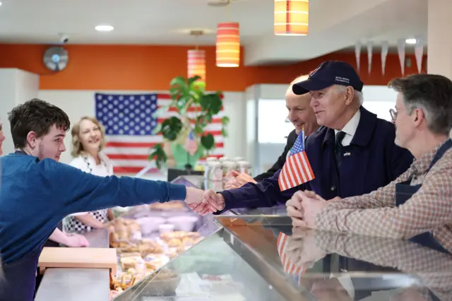 Joe Biden shakes hand of young man in a cafe in Dundalk, Ireland